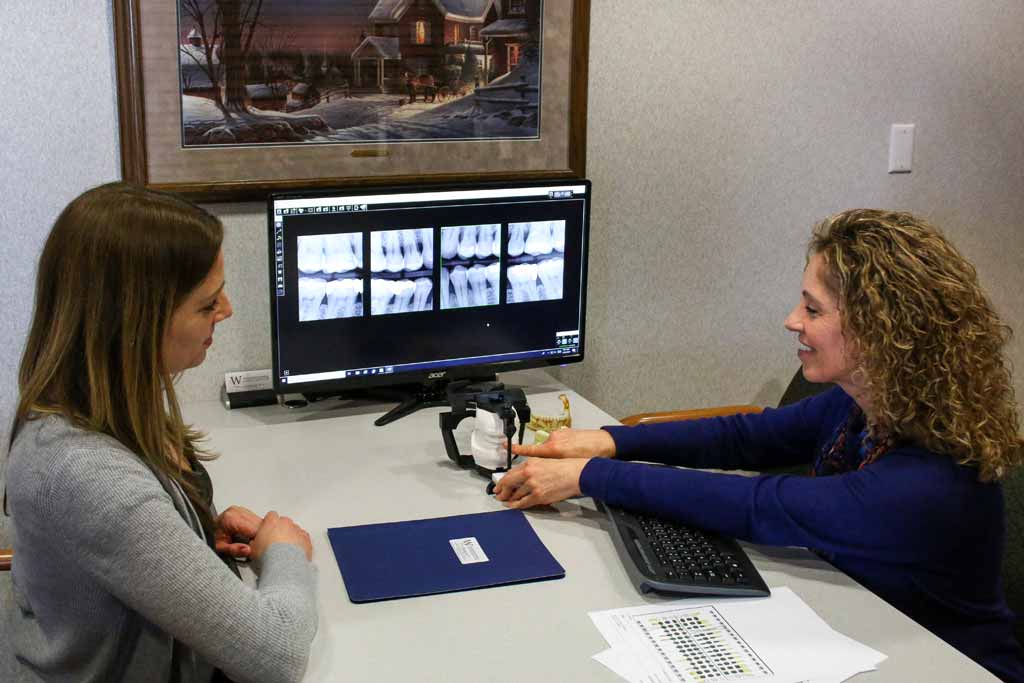 A dental hygienist showing the jaw model along with explaining an x-ray to a patient at Wanserski Dental Center for Complex Dentistry in Wausau, WI.